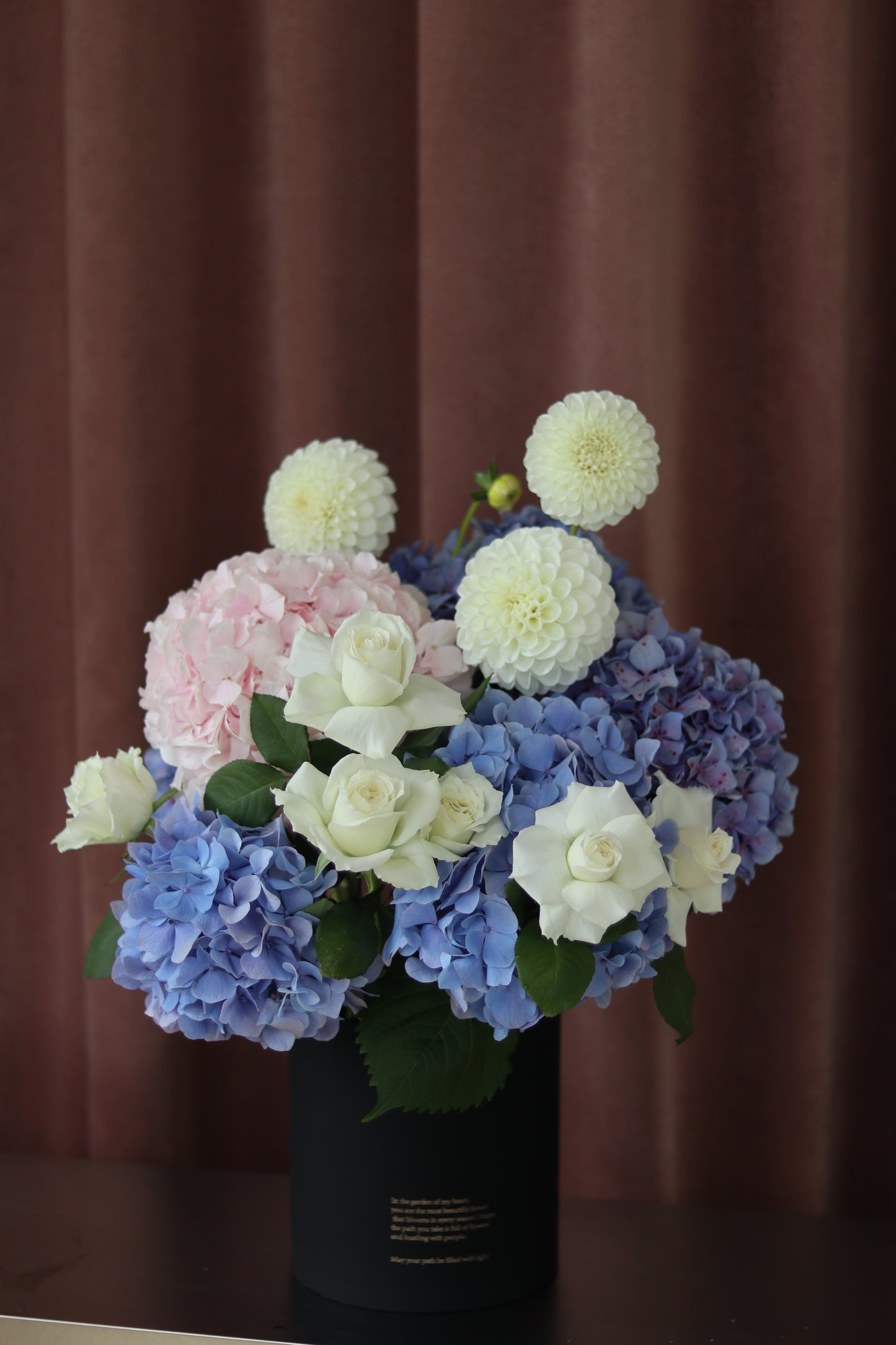 Full pastel hydrangea hug bucket featuring blue, pink and white hydrangea blooms