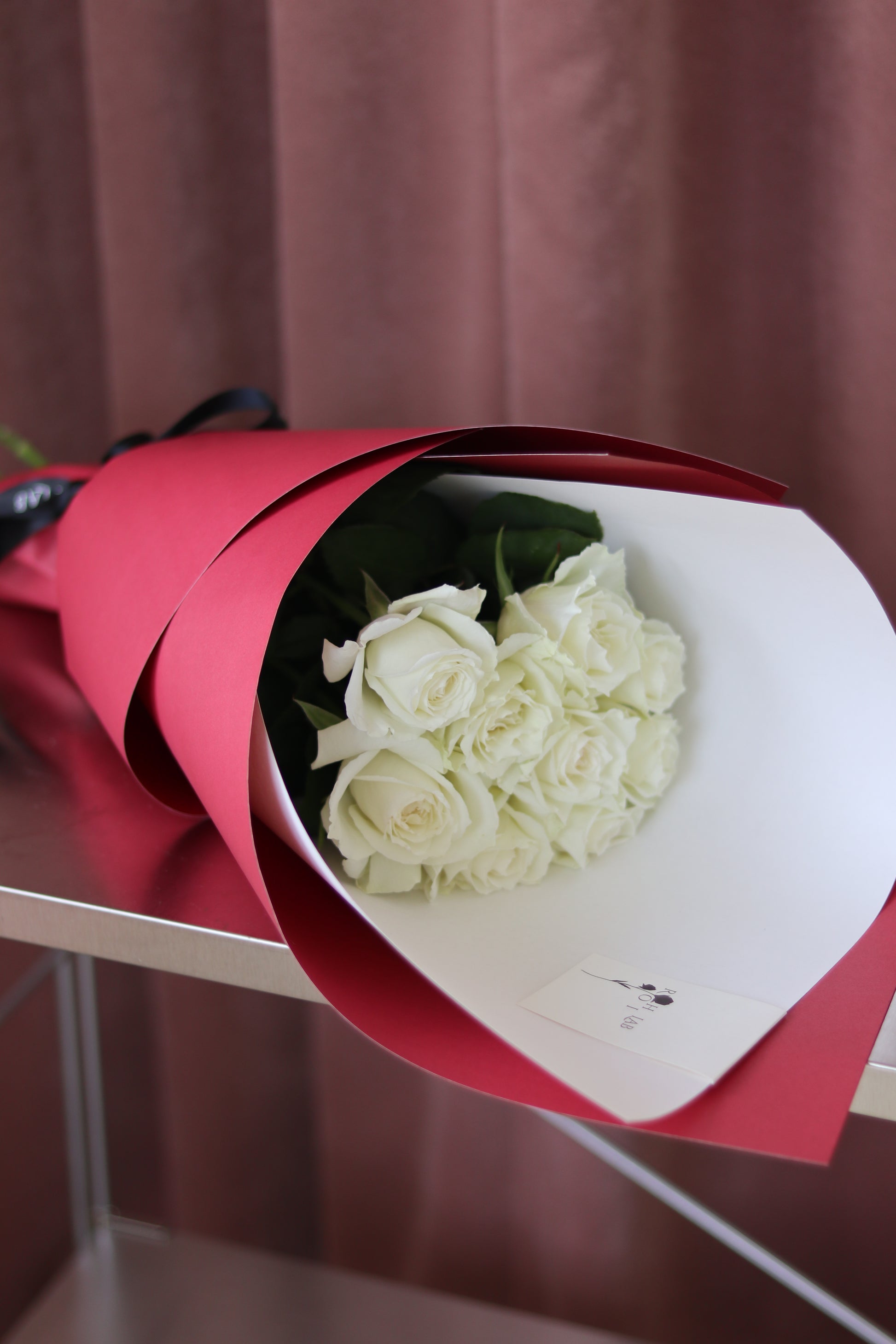Top view of white rose bouquet with bold red wrapping, minimalist luxury flower arrangement