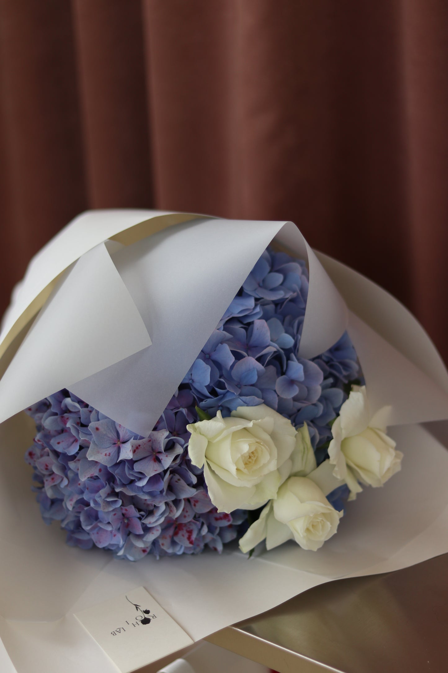 Soft Bloom flower arrangement featuring blue hydrangeas and ivory roses