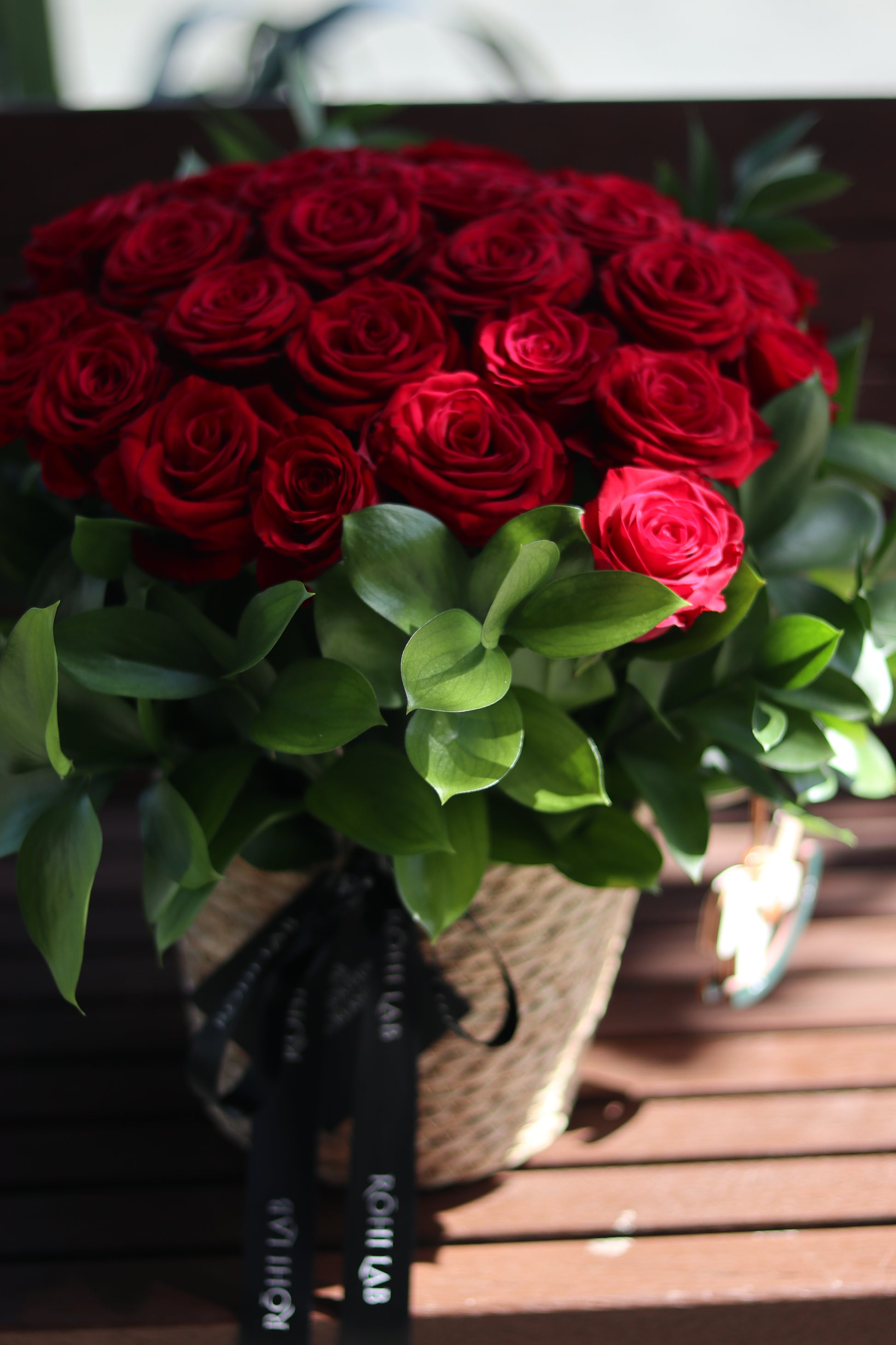 Romantic red rose basket arrangement with premium roses and natural greenery
