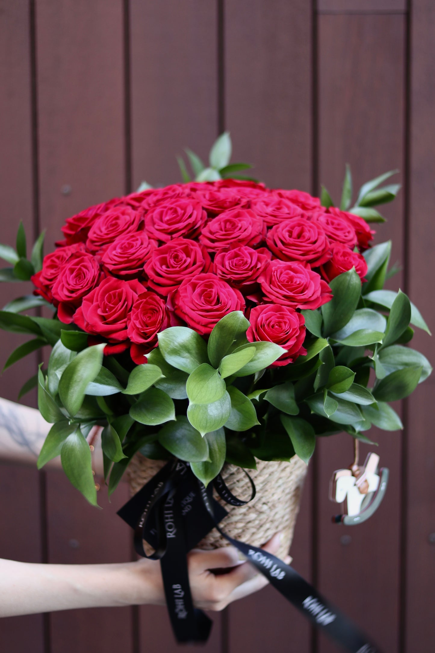 Romantic red rose basket arrangement with premium roses and natural greenery
