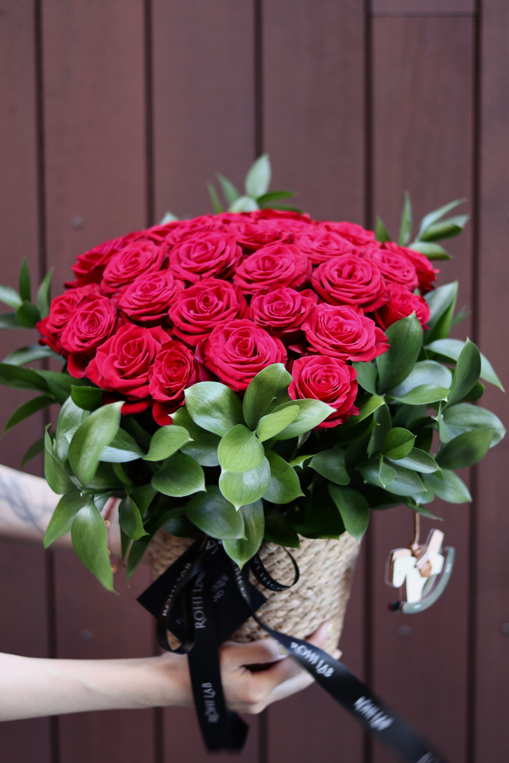 Romantic red rose basket arrangement with premium roses and natural greenery
