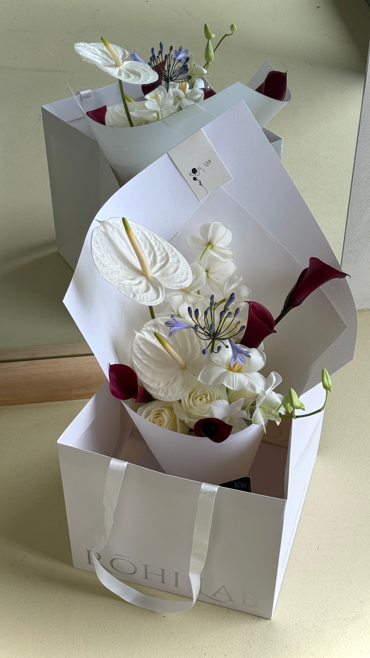 White and Burgundy Flower Bouquet with elegant white wrapping, featuring roses, anthuriums and burgundy accents