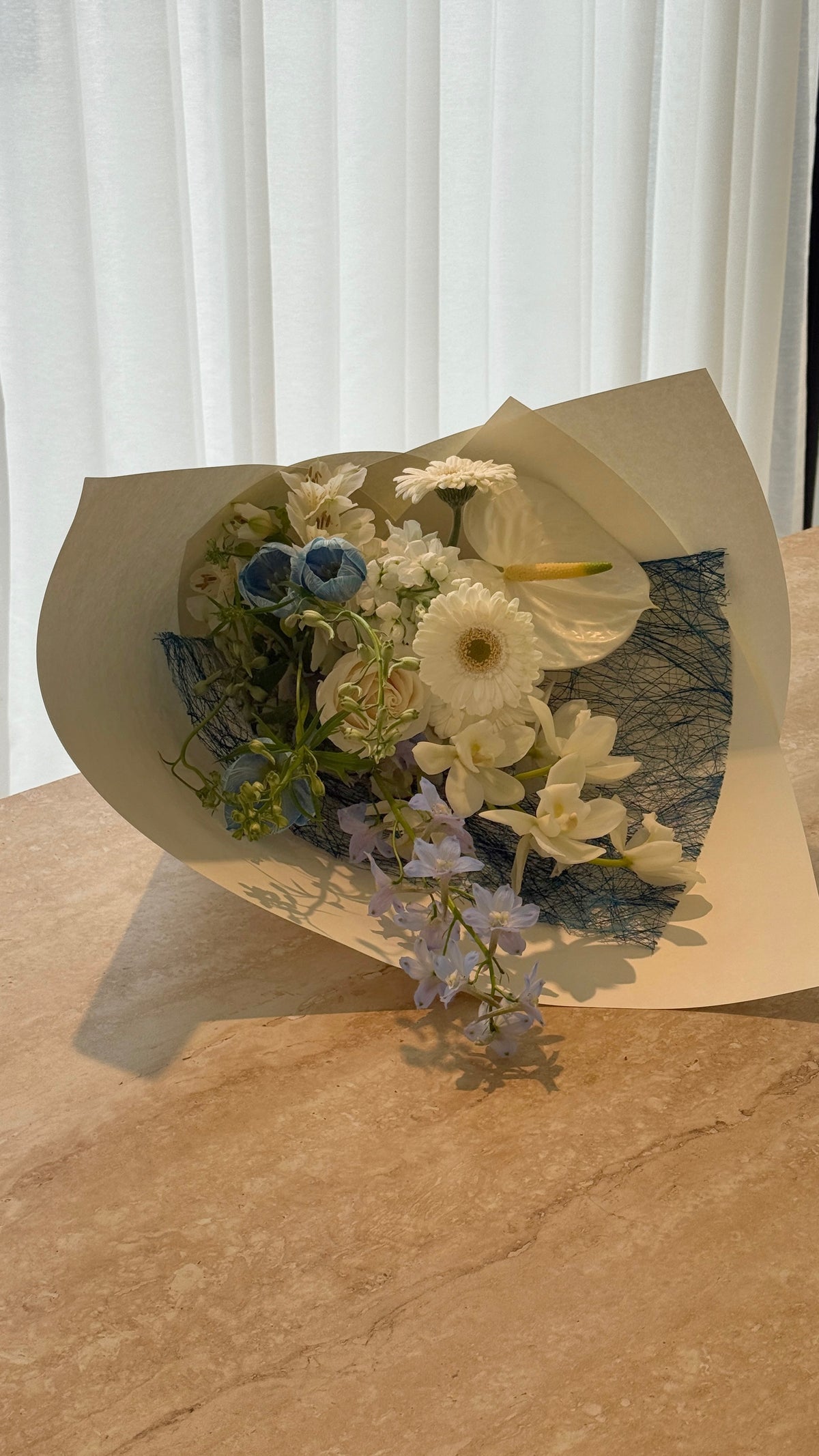 Daydream flower bouquet with soft blue and white blooms displayed on a wooden table