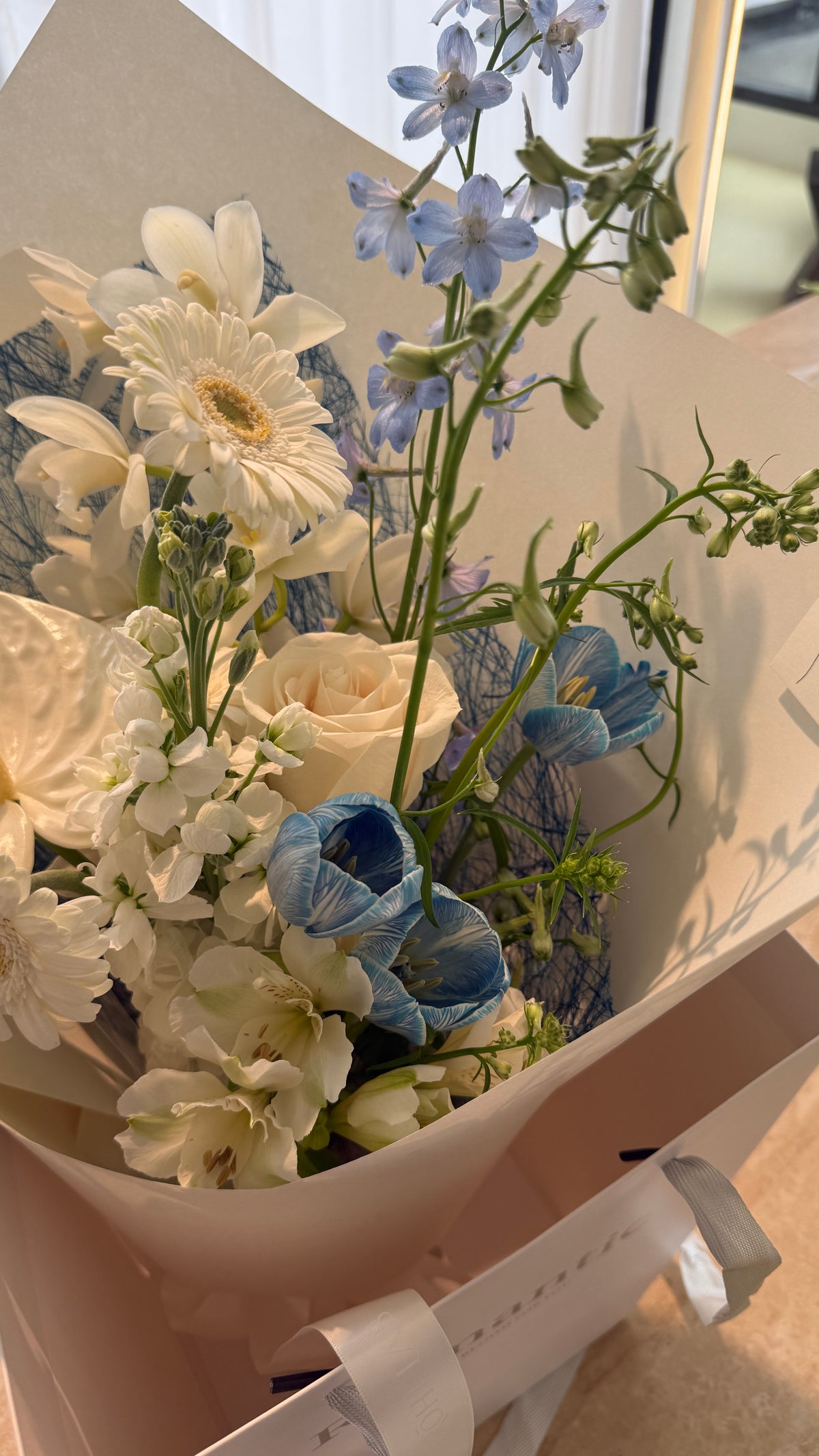 Handheld blue and white flower bouquet featuring delicate seasonal blooms and natural textures