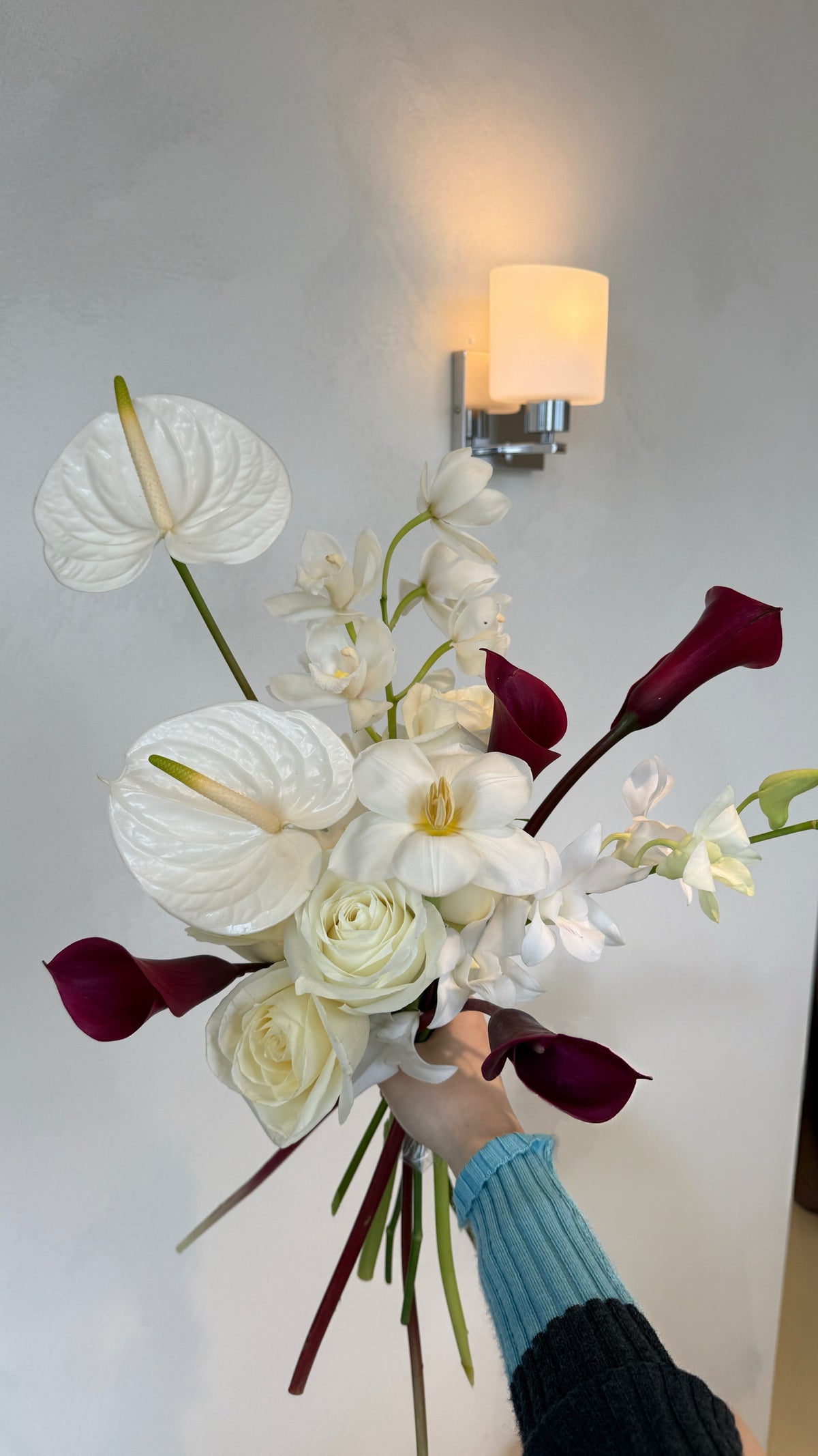 Handheld Dark Romance bouquet with white anthuriums, burgundy calla lilies and white roses, handcrafted by Rōhi Lab