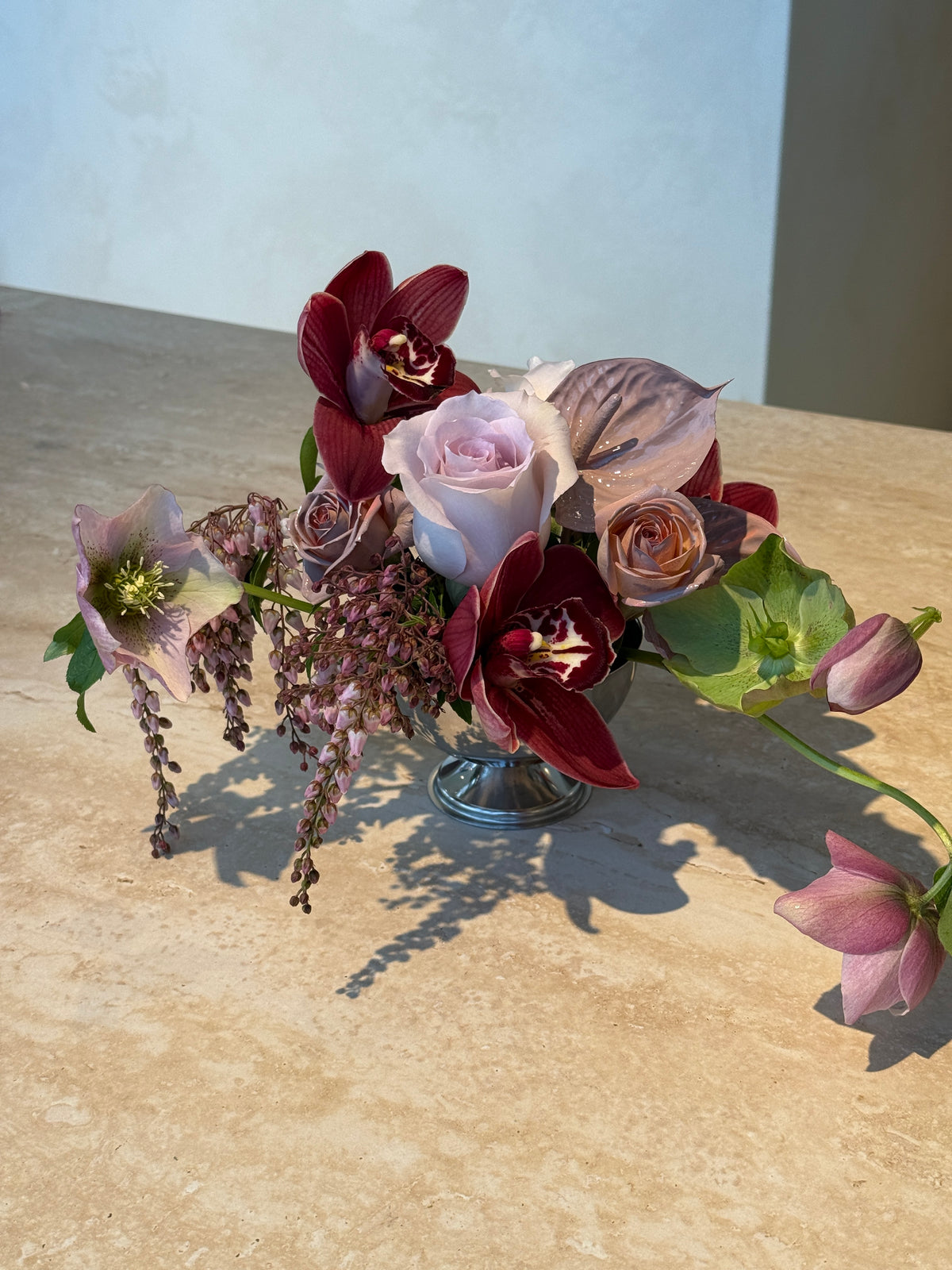 Custom Table Flower Arrangement in a stainless steel bowl with burgundy and seasonal blooms on a wooden table