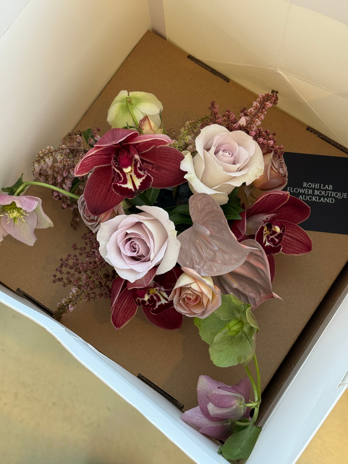 Overhead view of Fleurs de table seasonal floral arrangement with pink and burgundy flowers in a steel bowl