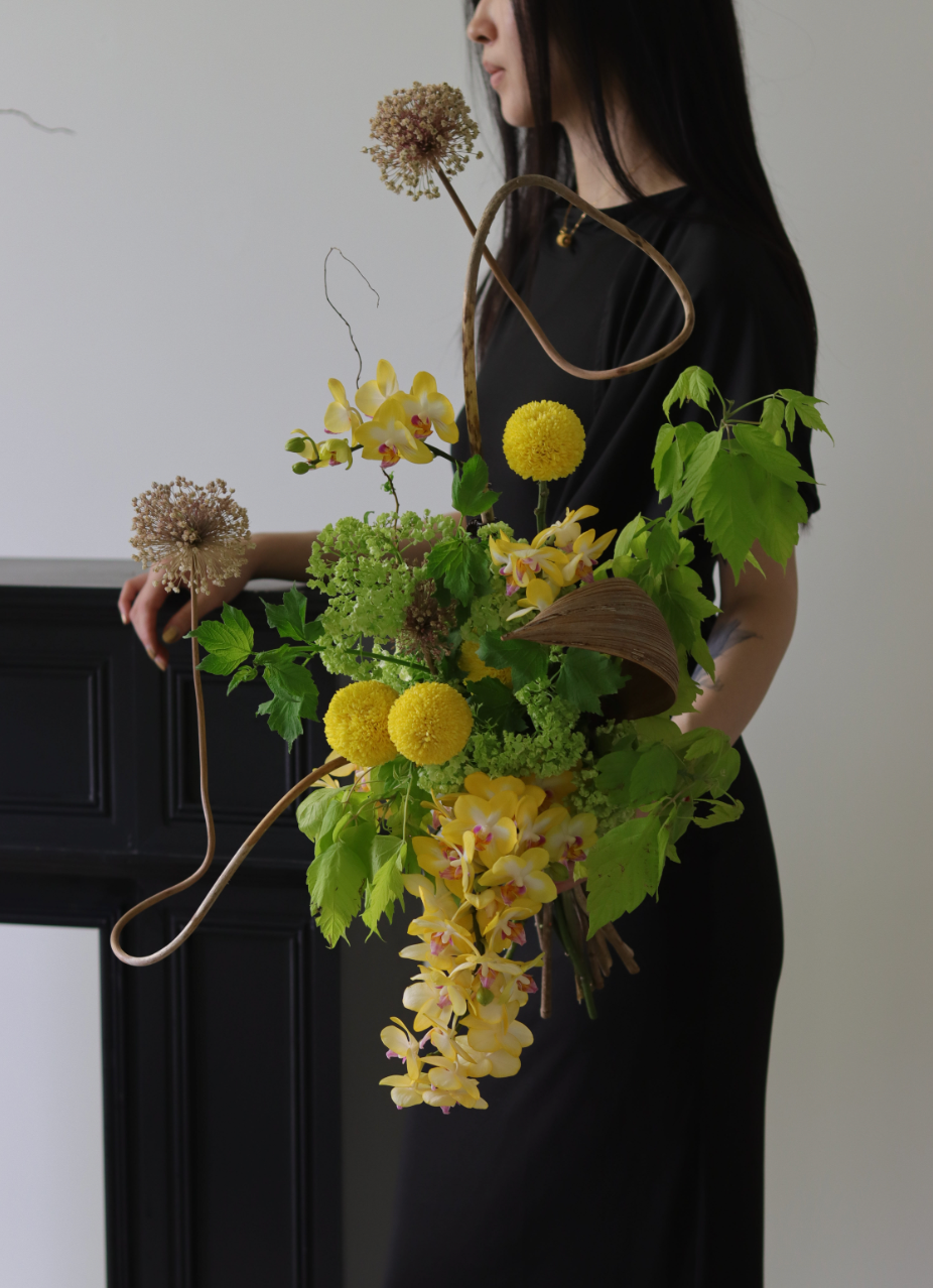 Contemporary sculptural floral arrangement with cascading yellow orchids and greenery