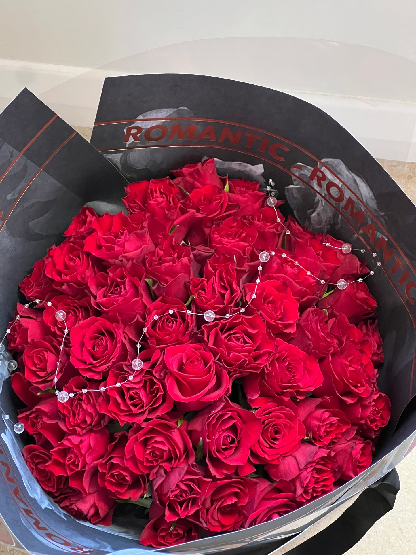 Close-up of premium red roses arranged in a full round bouquet with modern wrapping