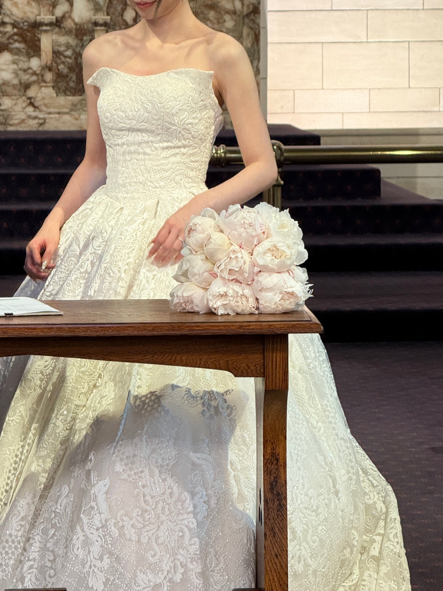 Soft blush peony bridal bouquet held by bride in lace wedding dress