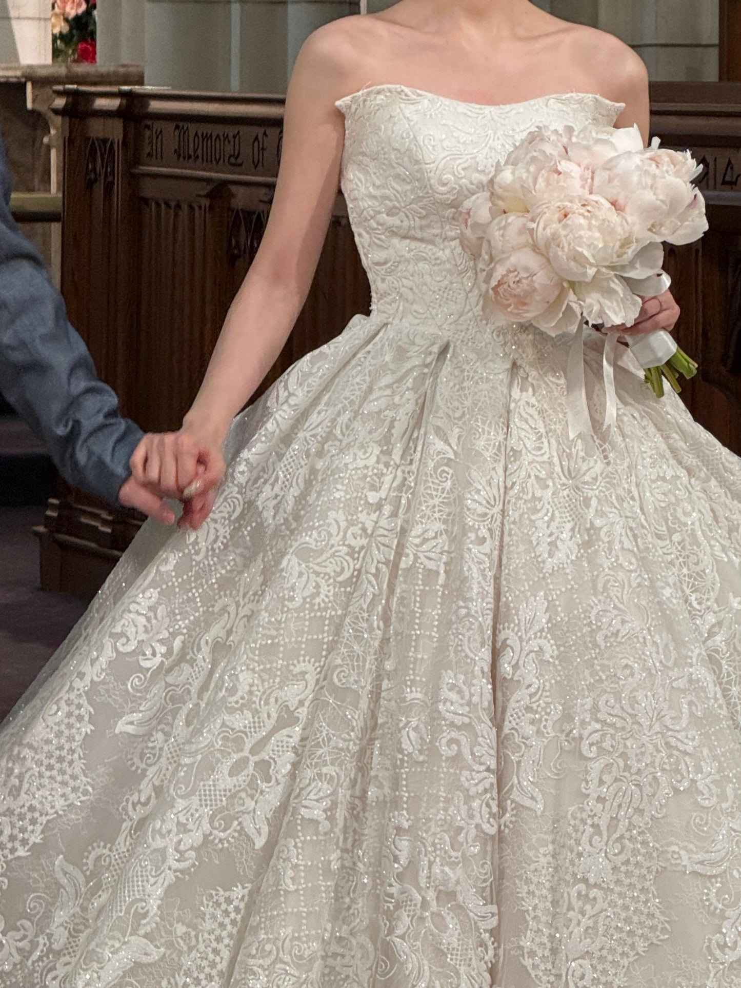 Soft blush peony bridal bouquet held by bride in lace wedding dress