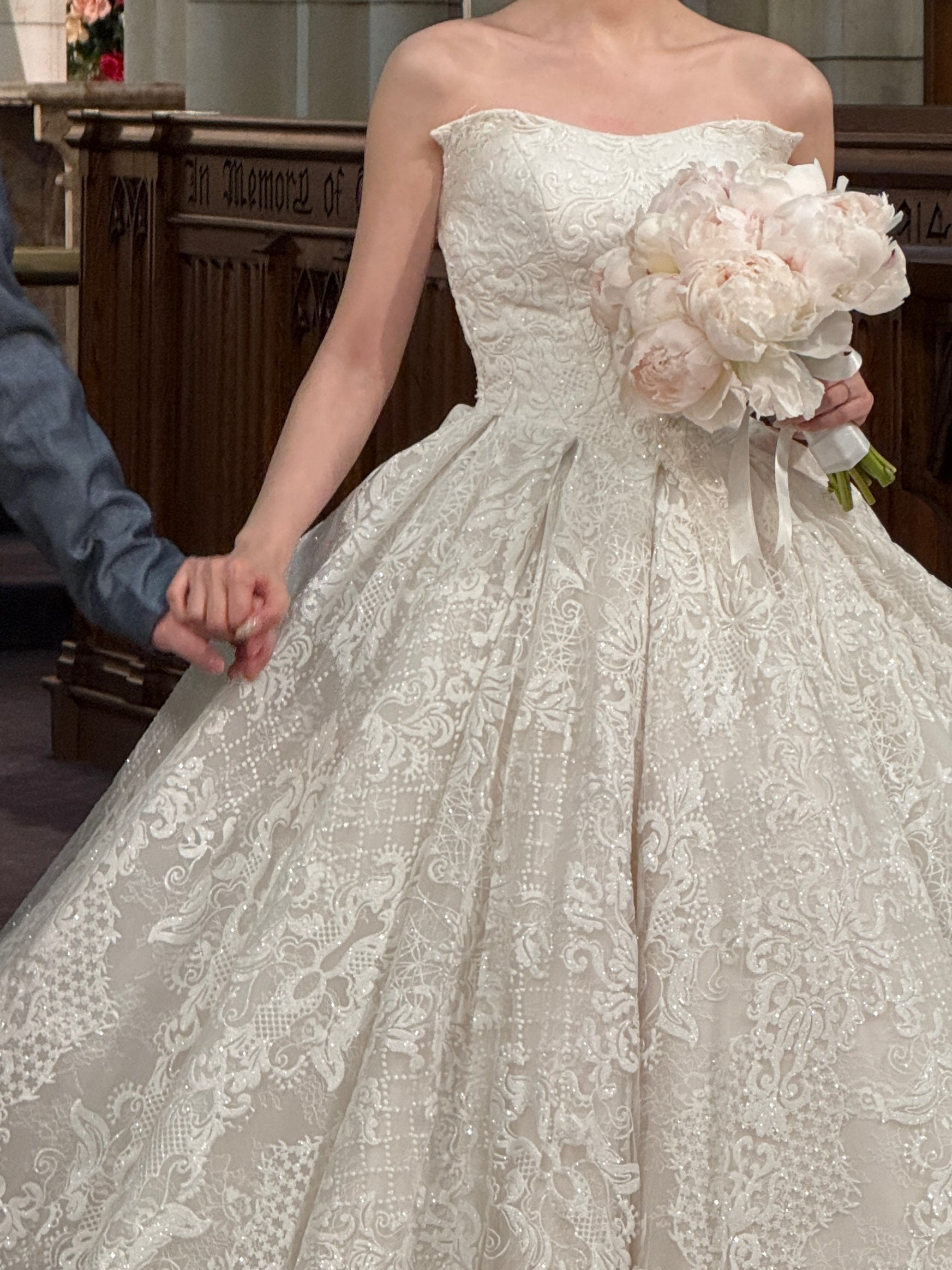 Soft blush peony bridal bouquet held by bride in lace wedding dress